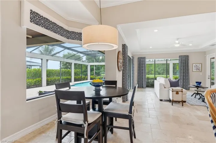 Open-concept living area featuring light-toned tile flooring, a tray ceiling with recessed lighting, and direct access to a screened lanai with a swimming pool