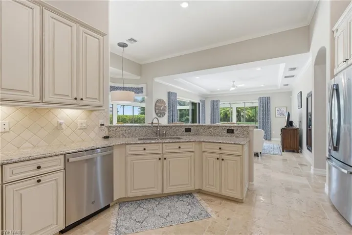 Kitchen with light-toned cabinetry, granite countertops, stainless steel appliances, and a diagonal tile backsplash