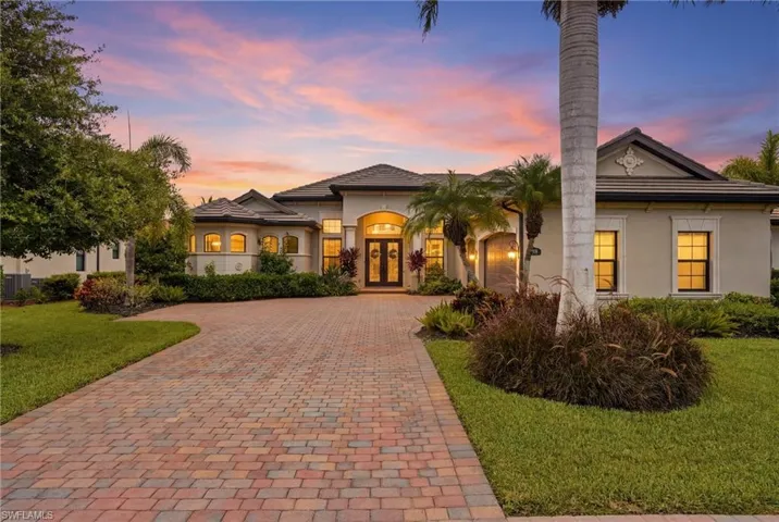 Elegant stucco exterior featuring a tiered roofline, arched entry, and decorative double doors