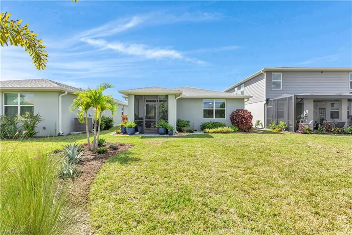 Rear view of property featuring a sunroom, a lawn, and stucco siding