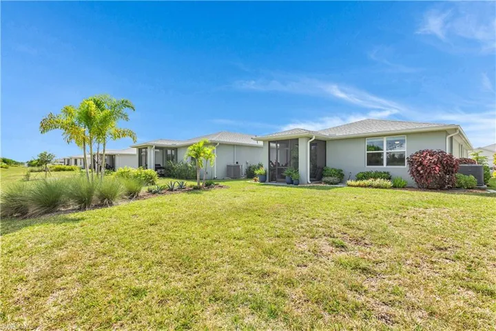 View of back of home featuring stucco siding, a large yard, and a enclosed screened Lanai/Patio.
