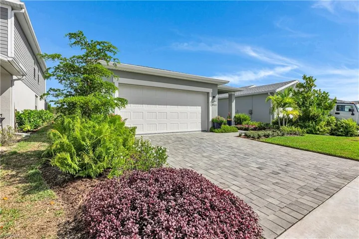 View of front of property featuring paver driveway, a front lawn, an attached two car garage with epoxy floor.