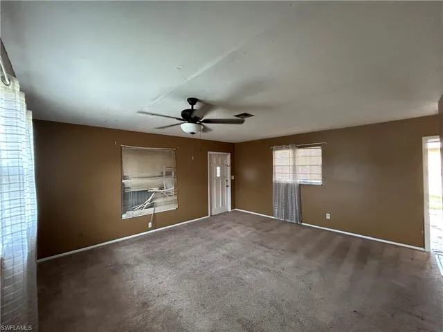Empty room featuring carpet flooring, baseboards, and a ceiling fan