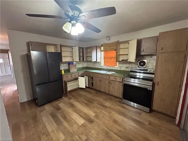 Kitchen with dark wood finished floors, a ceiling fan, open shelves, appliances with stainless steel finishes, and a sink
