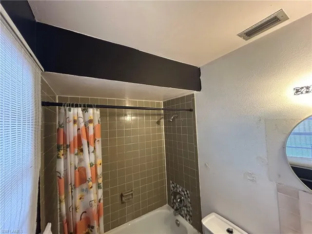 Full bath with shower / bath combination with curtain and visible vents