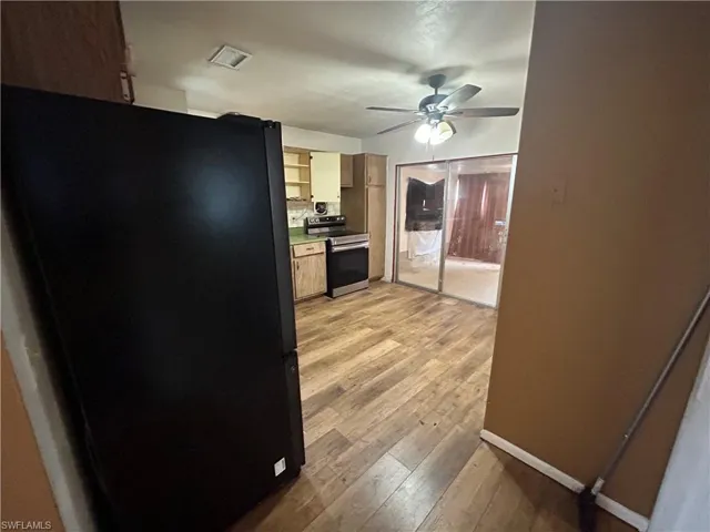 Kitchen featuring ceiling fan, freestanding refrigerator, stainless steel electric range oven, light wood finished floors, and baseboards
