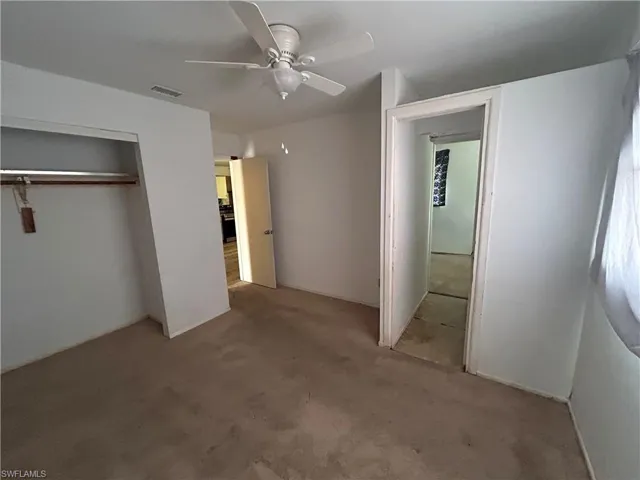 Unfurnished bedroom featuring ceiling fan, visible vents, a closet, and carpet floors