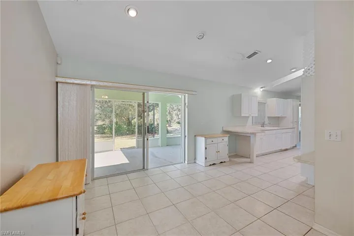 Kitchen with white cabinetry, light tile patterned flooring, wooden counters, and recessed lighting