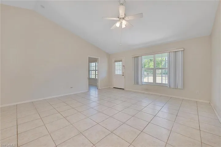 Spare room featuring light tile patterned floors, ceiling fan, and high vaulted ceiling