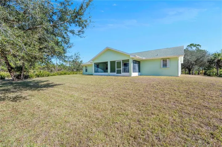 Back of property featuring a lawn, a sunroom, and stucco siding