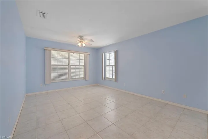 Empty room featuring plenty of natural light, a ceiling fan, and light tile patterned flooring