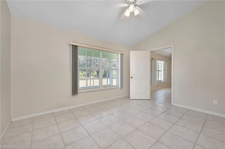 Unfurnished room featuring lofted ceiling, light tile patterned flooring, plenty of natural light, and ceiling fan