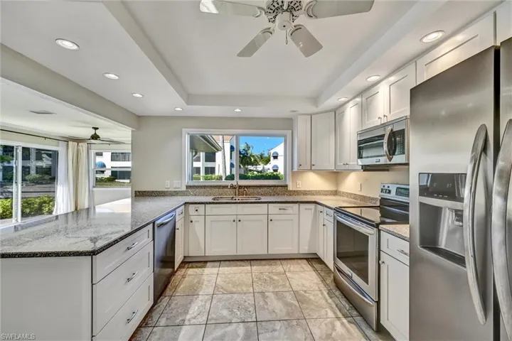 Kitchen featuring a ceiling fan, dark stone counters, stainless steel appliances, white cabinets, and recessed lighting