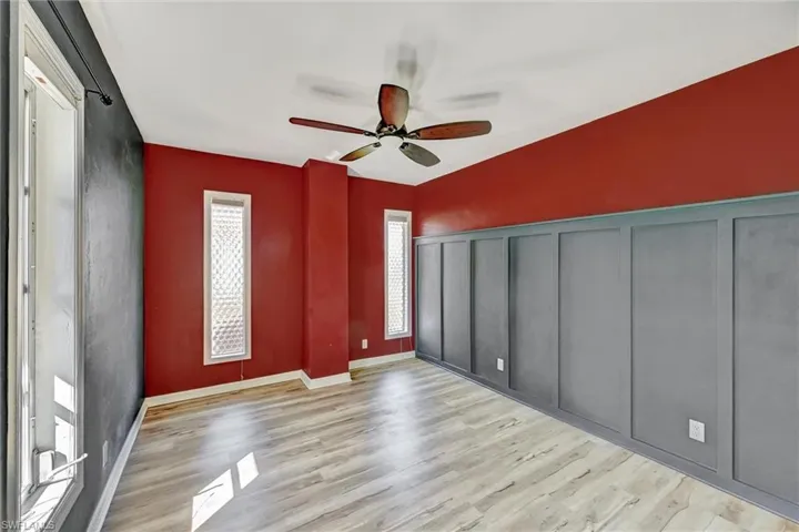 Unfurnished bedroom featuring ceiling fan, light wood finished floors, and a decorative wall