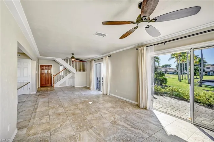 Unfurnished living room with ornamental molding, a ceiling fan, and stairs