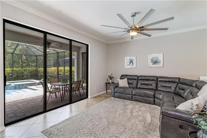 Living room featuring ceiling fan, ornamental molding, and light tile patterned floors