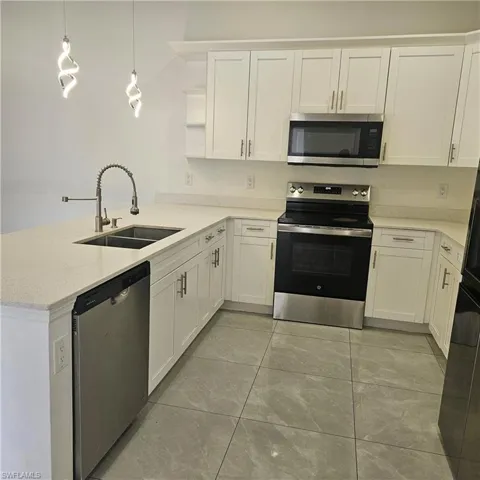 Kitchen featuring stainless steel appliances, a peninsula, white cabinets, hanging light fixtures, and open shelves