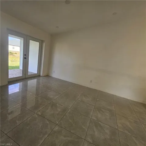 Tiled spare room with baseboards and french doors