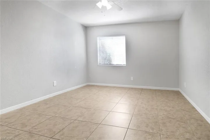 Spare room with light tile patterned floors, baseboards, and ceiling fan