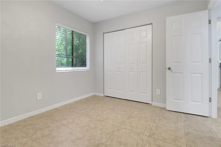 Unfurnished bedroom featuring a closet, light tile patterned floors, and baseboards