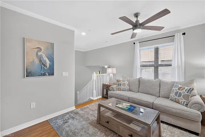 Crown molding, wood-style laminate flooring with lighted ceiling fan an recessed lighting.