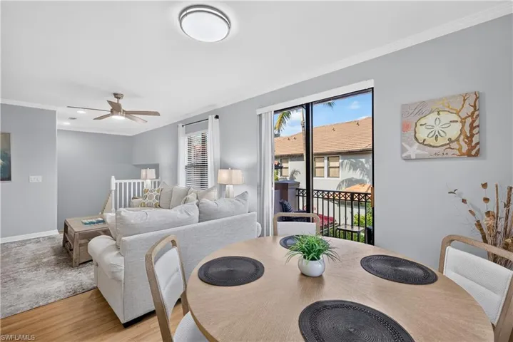 Open-concept living area with wood-finish laminate flooring, a contemporary ceiling fan, and sliding doors to the balcony.