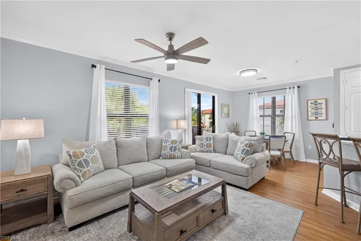 Living area featuring crown molding, ceiling fan, and wood-finish laminate flooring