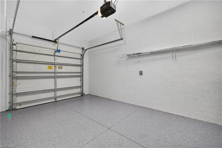 Attached garage featuring a finished floor coating, an automatic garage door opener, and wall shelving
