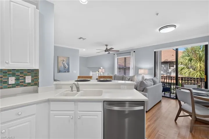 Kitchen featuring white cabinetry, solid surface countertops, tile backsplash, and a breakfast bar.