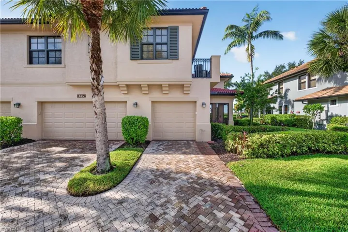 One car attached garage, with a paver driveway, and a second-story balcony with iron railing