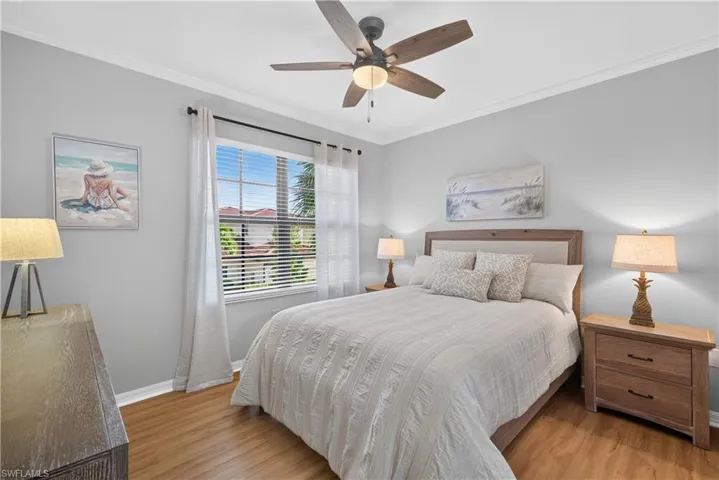 Wood-finish laminate flooring, crown molding, and a ceiling fan with integrated lighting