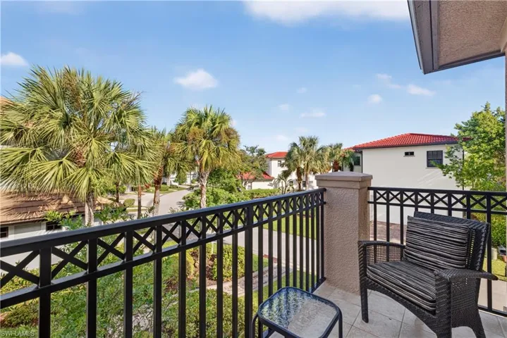 Private outdoor balcony with a wrought iron railing, textured stucco pillar, and tiled flooring