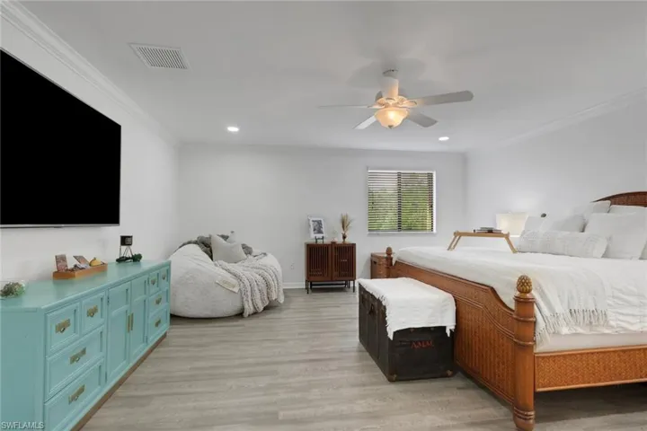 Wood-finish flooring, crown molding, and a multi-blade ceiling fan with integrated lighting