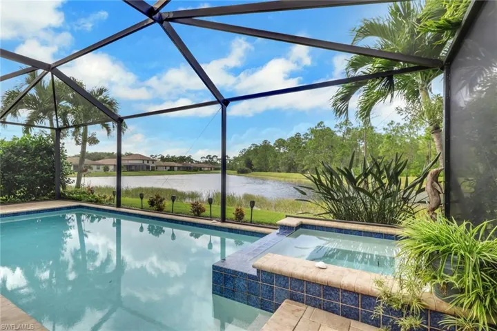 Screened lanai featuring an in-ground swimming pool, integrated spa, tiled water line finish, and stone paver decking