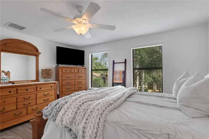 Ceiling fan with integrated light fixture and neutral wall finishes, featuring two windows with horizontal blinds