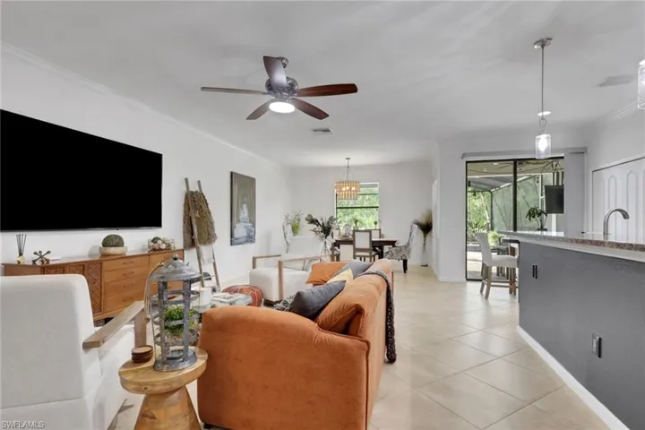 Open-concept main living area featuring large-format ceramic tile flooring, a multi-blade ceiling fan, recessed lighting, pendant accent lighting, and sliding glass doors