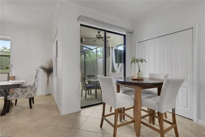 Neutral-toned tile flooring, crown molding, double-panel sliding glass doors, and a double-door closet with recessed paneling