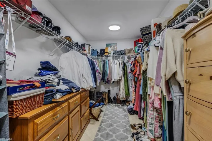 Walk-in closet featuring white wire shelving, wood-finish built-in cabinetry with drawers, and a ceiling-mounted light fixture