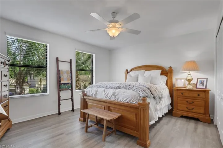 Neutral-toned interior space featuring wood-finish flooring, dual windows, and a ceiling-mounted light fixture with an integrated fan