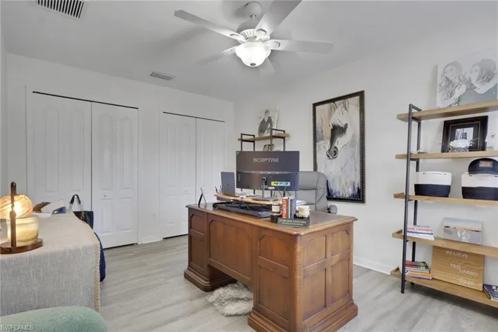 Room featuring wood-finish flooring, dual-panel closet doors, and a ceiling-mounted light fixture with a fan
