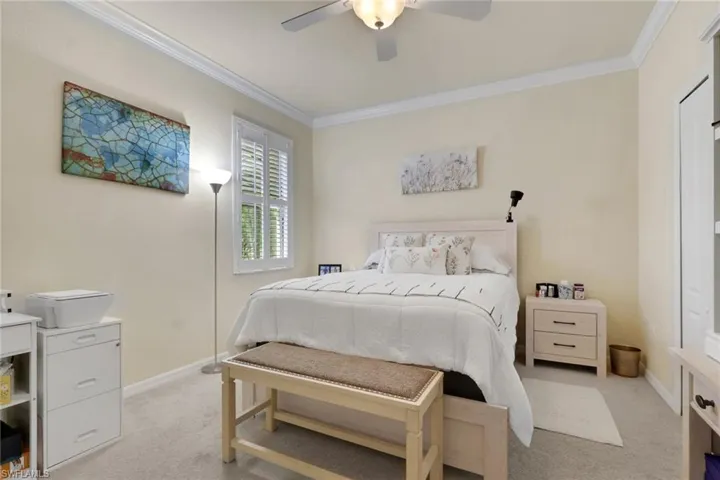 Room featuring crown molding, a ceiling fan with integrated light fixture, carpeted flooring, and a window with plantation shutters