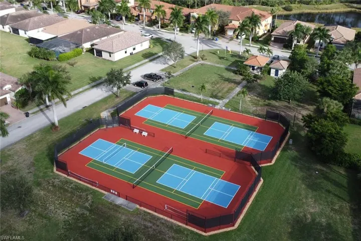 Community recreation area featuring four hard-surface tennis courts and perimeter black chain-link fencing