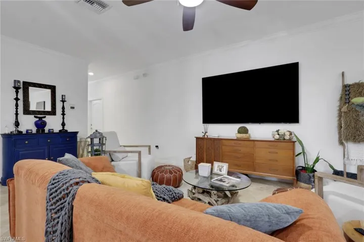 Living area featuring neutral-toned walls, high ceilings, stone-finish flooring, and a ceiling fan