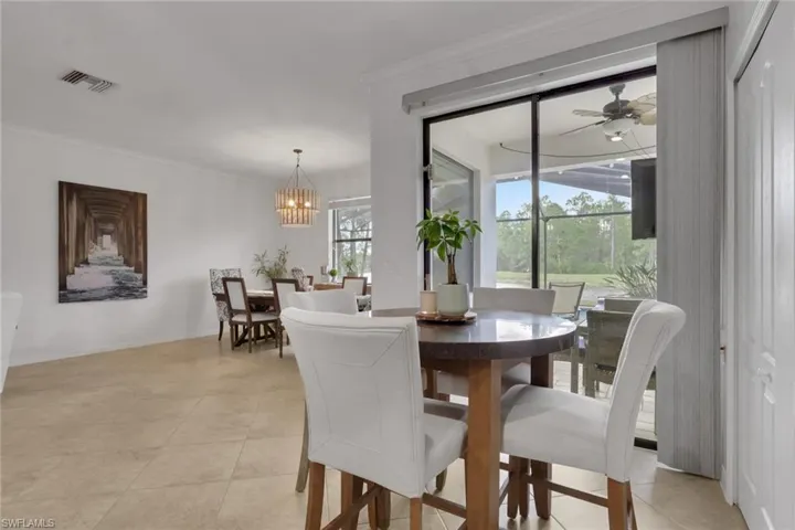 Neutral tile flooring, multi-light tiered chandelier, and sliding glass doors with exterior access