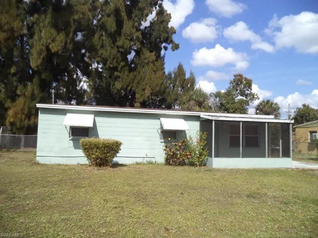 Rear view of property featuring a sunroom, a lawn, and fence