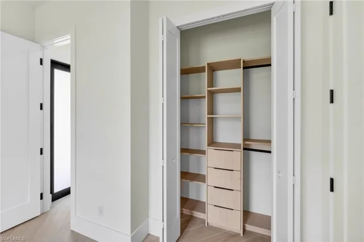 Custom closet system with light wood-finish shelving and integrated drawers, complemented by a hanging rod
