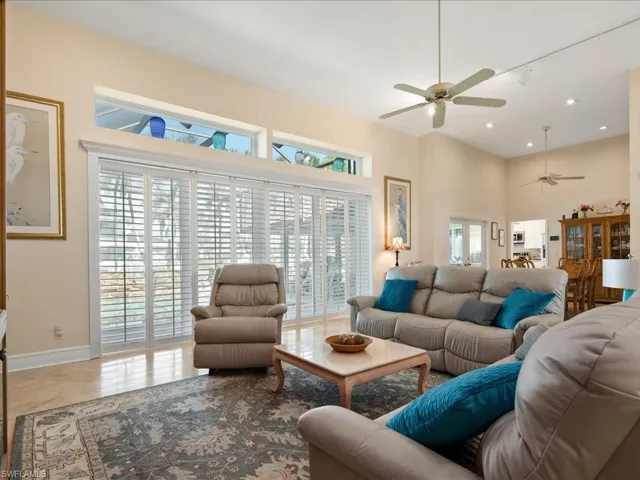 Living room with plenty of natural light, ceiling fan, and a high ceiling