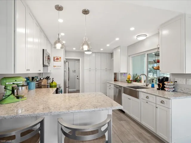 Kitchen with white cabinetry, kitchen peninsula, appliances with stainless steel finishes, and a breakfast bar