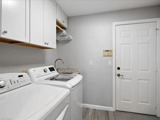 Laundry area with light hardwood / wood-style floors, cabinets, sink, and washing machine and clothes dryer