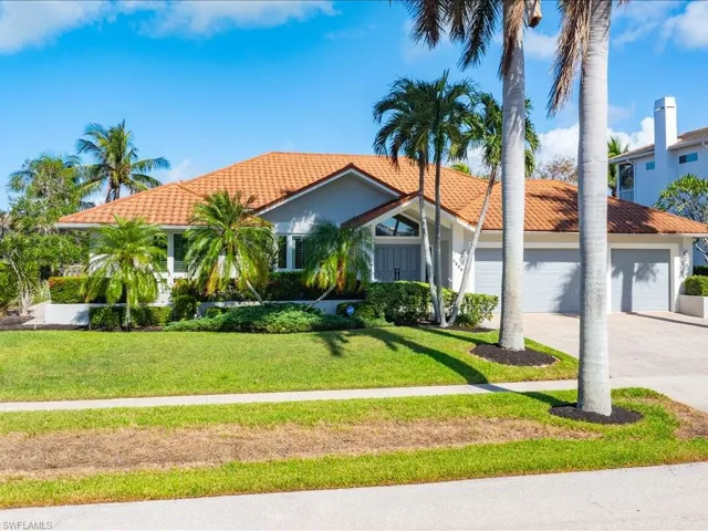 Marco Island waterfront home featuring a front lawn and a garage